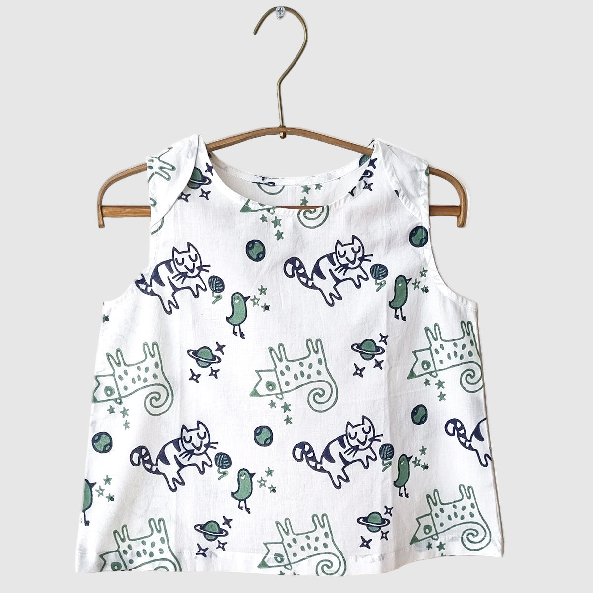organic cotton white sleeveless top with blue and green cat pattern on a wooden hanger against a white background for kids to wear during summer