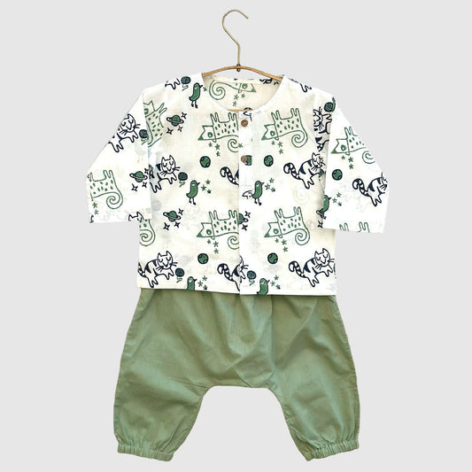 Children's outfit with patterned top and green pants on a hanger against a light gray background