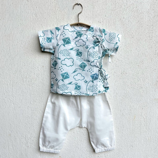 A white angarakha with tie-up closure and hand-block printed teal koi and sunshine patterns, and a pair of white pyjama pants with an elasticated waist and bottom hem, displayed on a hanger against a neutral background.