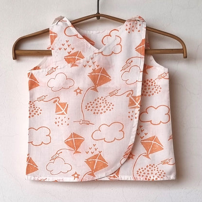 Children's sleeveless top with kite and cloud pattern on a wooden hanger against a white background