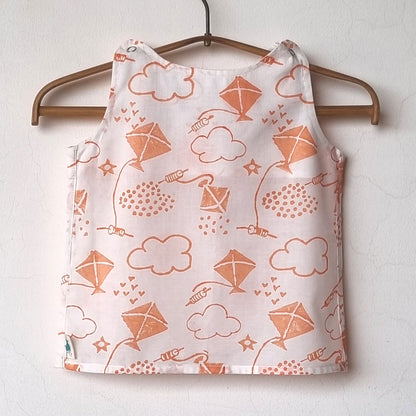 Children's tank top with kite and cloud pattern on a hanger against a white wall