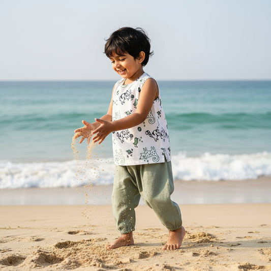 Children's outfit with a patterned top and green shorts on a hanger against a white background