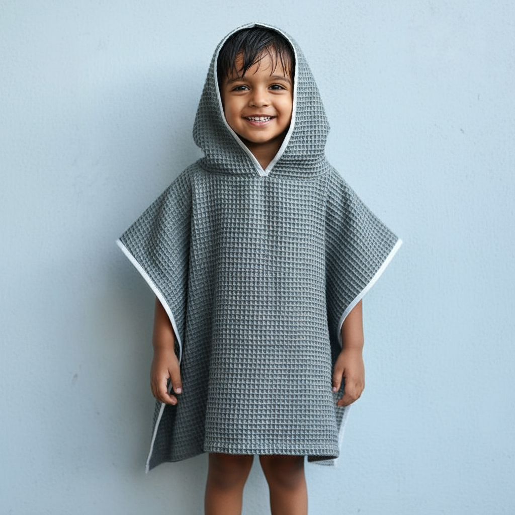 Child wearing a gray hooded poncho against a light blue background