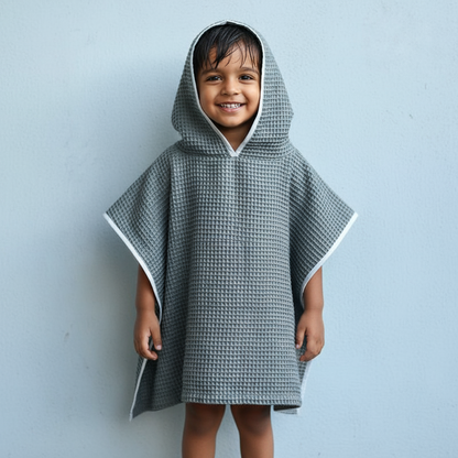 Child wearing a gray hooded poncho against a light blue background